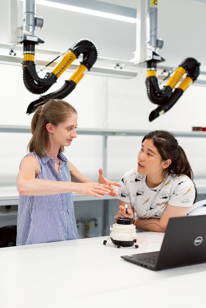 Two women engineers discussing a project in a high-tech lab environment.