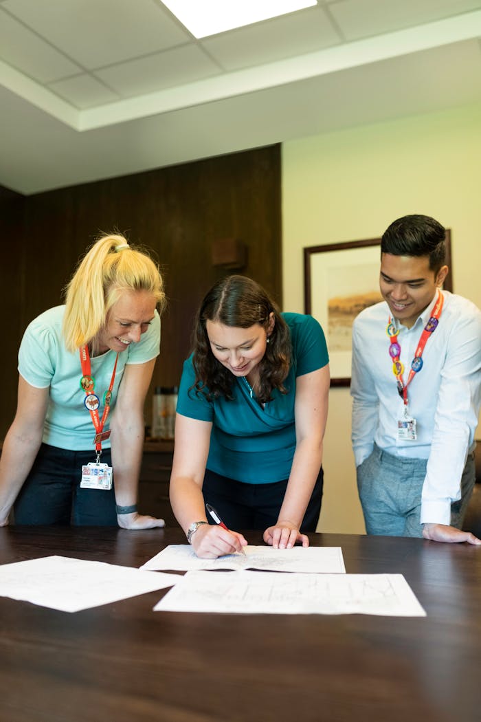 Three colleagues collaborating on a project around an office table, fostering teamwork and cooperation.